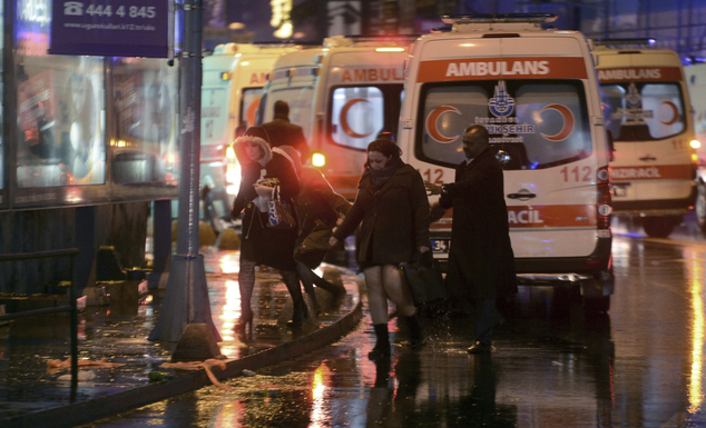 People leave as medics and security officials work at the scene after an attack at a popular nightclub in Istanbul, early Sunday, Jan. 1, 2017. Turkey's state-run news agency says an armed assailant has opened fire at a nightclub in Istanbul during New Year's celebrations, wounding several people.(IHA via AP)