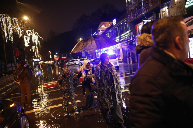 People walk under rain near the scene of an attack in Istanbul, early Sunday, Jan. 1, 2017. Turkey's state-run news agency said an armed assailant has opened fire at a nightclub in Istanbul during New Year's celebrations. (AP Photo/Halit Onur Sandal)